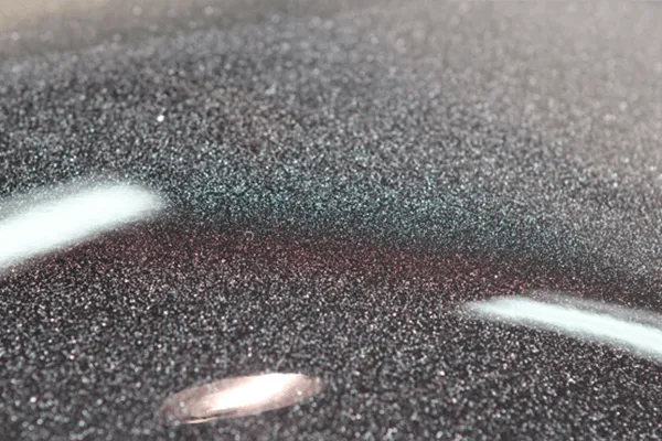 Paint overspray and industrial fallout bonded to dark metallic paint